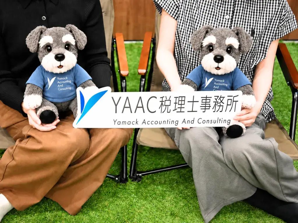 事務所スタッフ二人で事務所のマスコットキャラクターを持っている様子